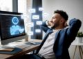 Man in a suit relaxes at his desk, smiling at a computer screen displaying a virtual assistant and email icons.